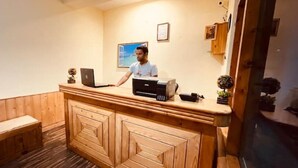 A reception desk with a laptop, a printer, and a small plant. - Queen Room Snow Mountain View With Balcony (himachal)