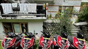A row of red and white scooters parked in front of a building with a balcony. - Queen Room Snow Mountain View With Balcony (himachal)