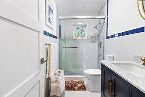 A modern bathroom with a glass-enclosed shower, a white toilet, and a marble sink. - Luxe Cozy Canal Loft Retreat in Nassau Bahamas (Nassau)