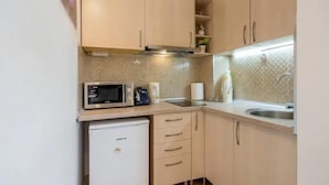 Una cucina compatta con forno a microonde, macchina del caffè e piccolo frigorifero.