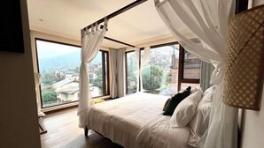 Un dormitorio con una cama grande, vistas a la ciudad y un balcón.