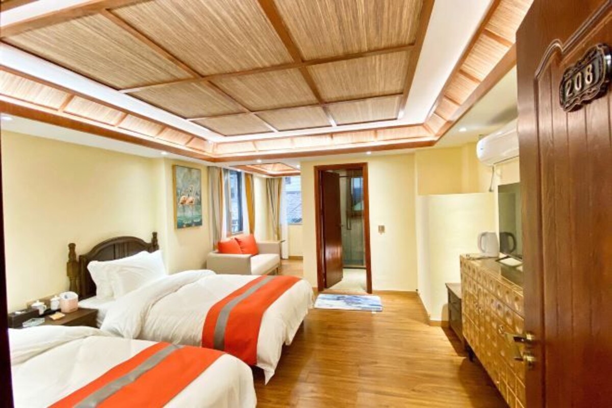 Una habitación de hotel con dos camas, techo de madera, cómoda y una puerta con el número 208.
