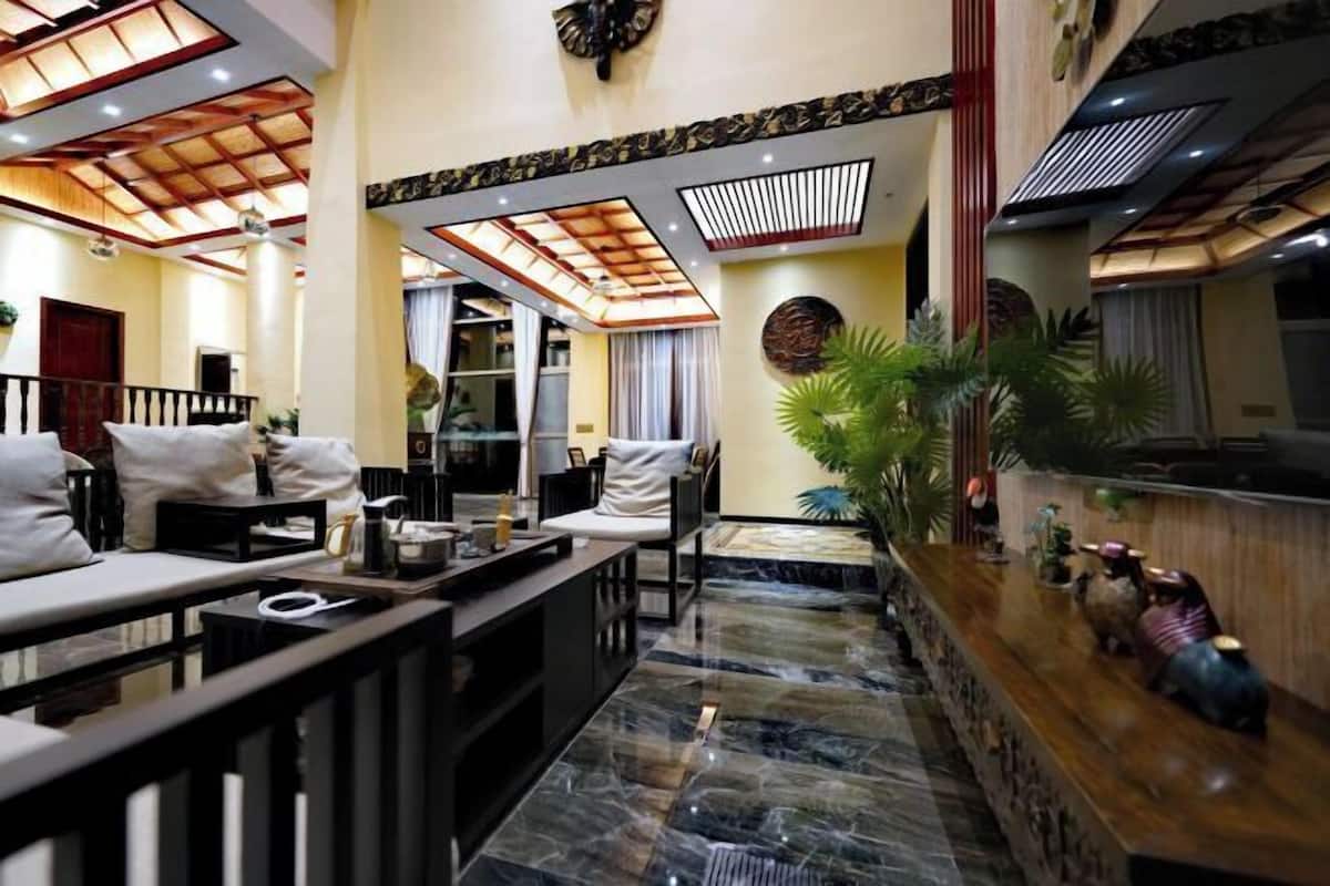 A hotel lobby with a reception desk, seating area, and a decorative wall with a clock.
