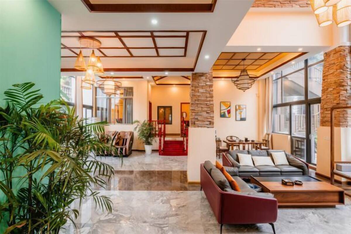 A spacious lobby with a marble floor, a red sofa, and a staircase leading to upper floors.
