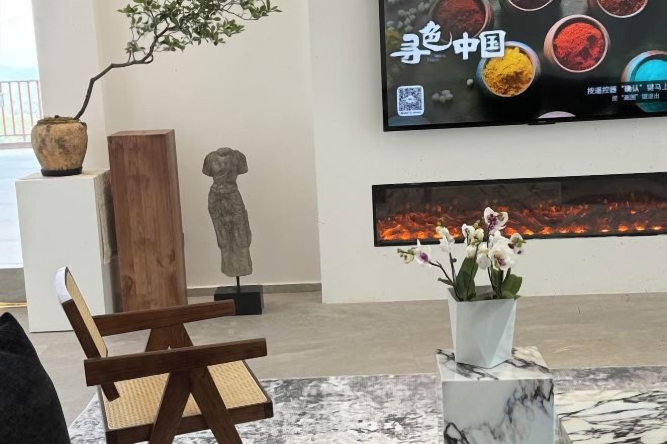 Una stanza con una sedia di legno, un tavolino con un vaso di fiori, un quadro grande appeso al muro e una scultura.