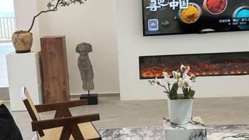 Una stanza con una sedia di legno, un tavolino con un vaso di fiori, un quadro grande appeso al muro e una scultura.