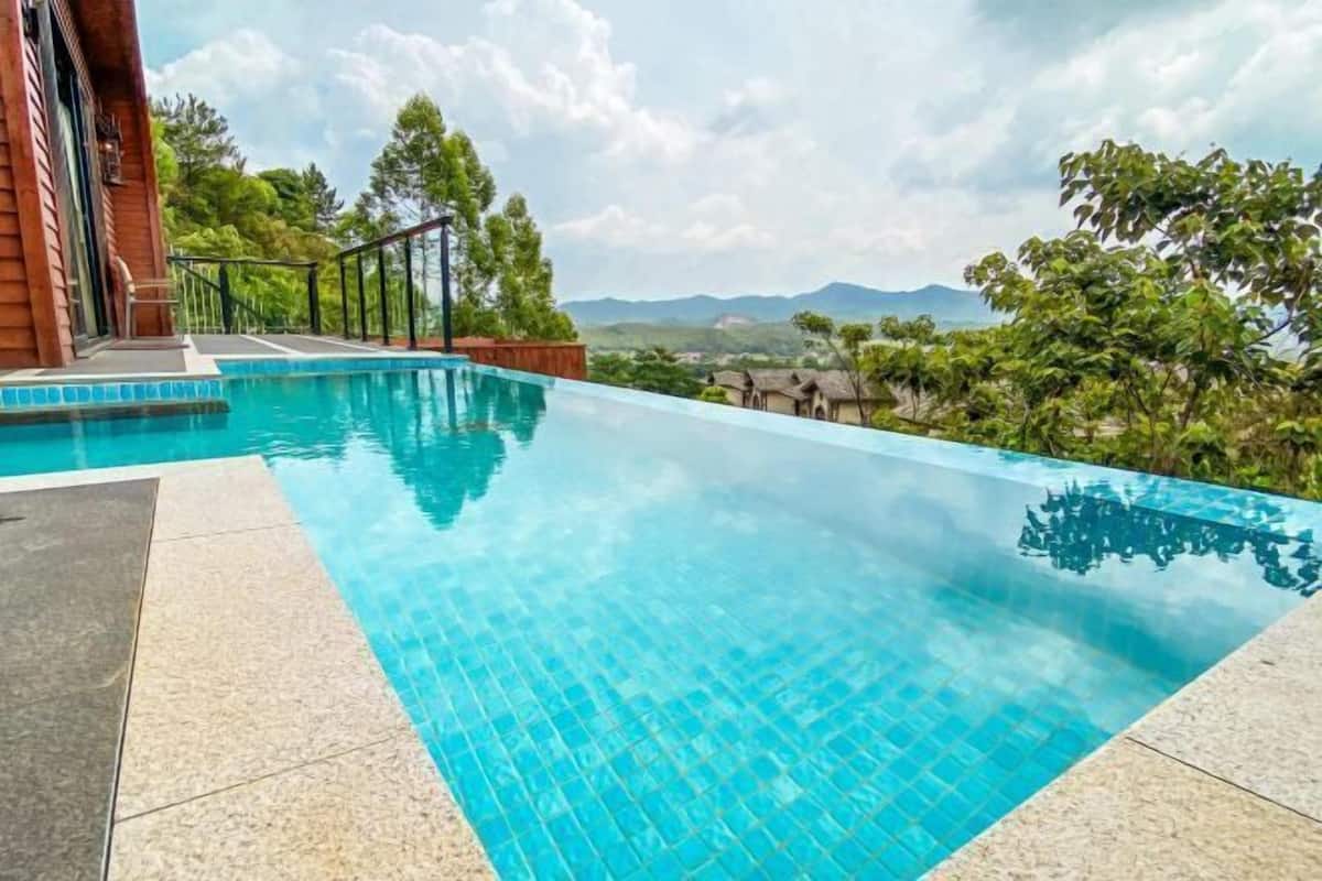 A swimming pool with clear blue water, surrounded by a tiled deck and a wooden fence.