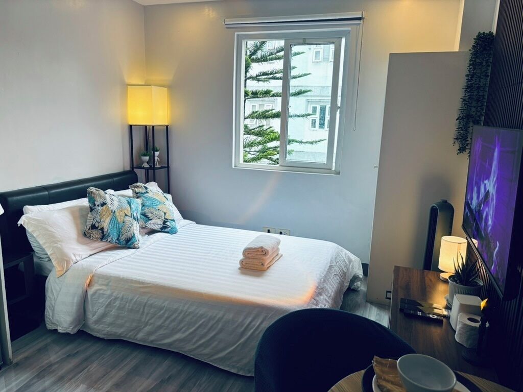 Une chambre d’hôtel avec un lit, une fenêtre donnant sur un paysage agréable, un bureau avec une lampe et un téléviseur.