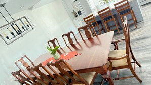 Un comedor con una mesa y sillas de madera, un florero con una planta y un corredor decorativo.