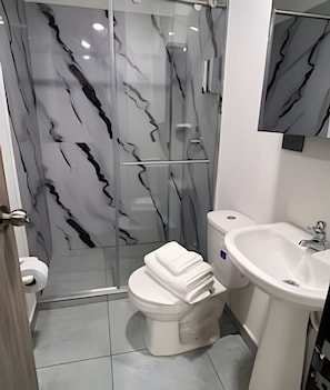 A modern bathroom with a glass shower enclosure, a toilet, and a sink. - Elite Studios (Armenia)