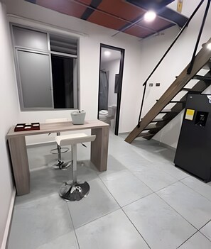 A modern, well-lit room with a wooden dining table, a small stool, and a refrigerator. - Elite Studios (Armenia)