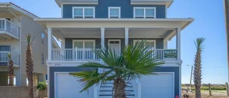 A two-story house with a front porch, a garage, and a small staircase leading to the entrance.
