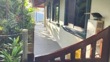 A covered outdoor area with a wooden gate, a staircase, and a view of greenery.