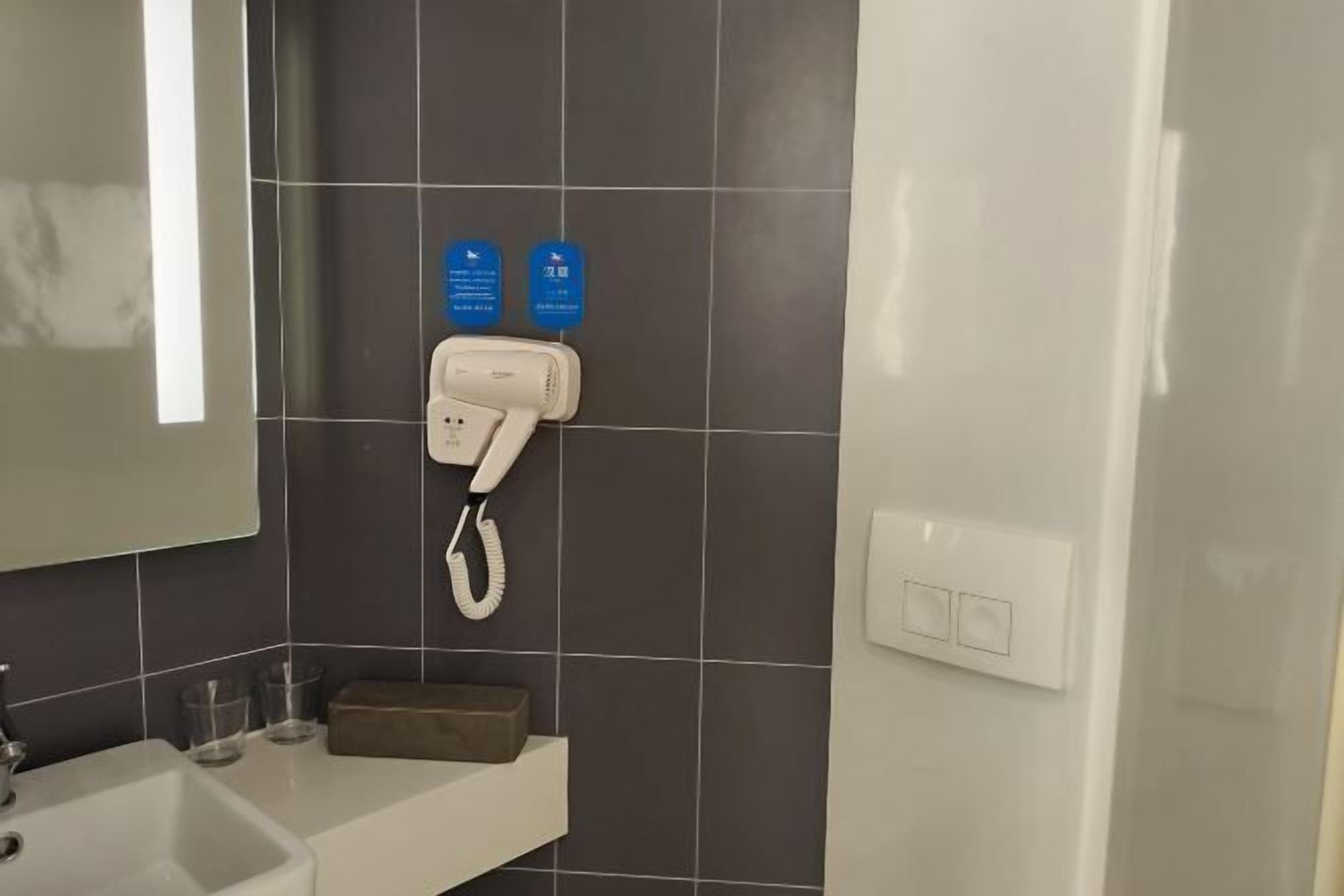 A bathroom with a white sink, a mirror, a towel rack, and a wall-mounted phone.