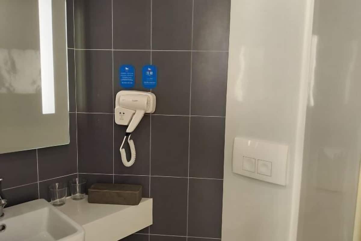 A bathroom with a white sink, a mirror, a towel rack, and a wall-mounted phone.