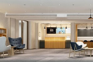 Eine moderne Hotelhalle mit Sitzgelegenheiten, einer Rezeption und Pendelleuchten.