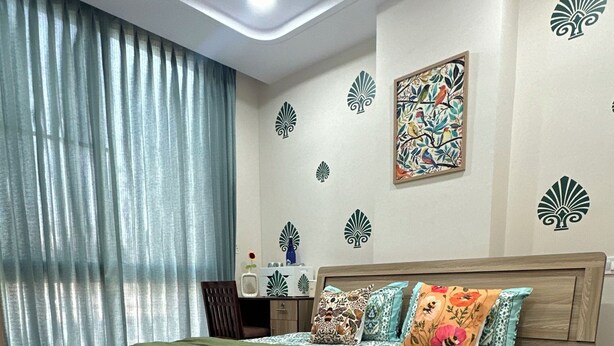 Un dormitorio con cama, ventilador de techo, mesita de noche y decoración en la pared.