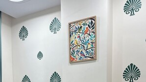 Un dormitorio con cama, almohadas, un escritorio y una pared con diseños decorativos.