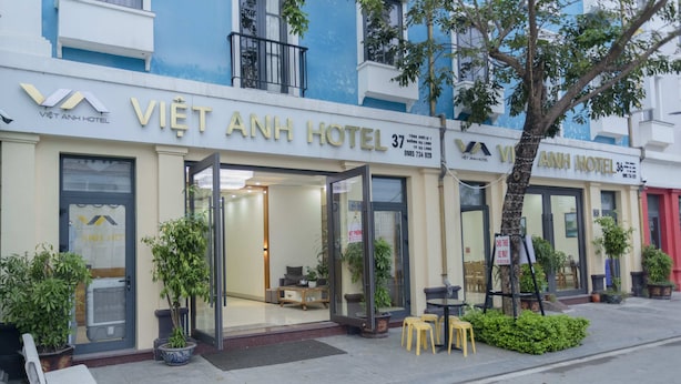 The exterior of Việt Anh Hotel, featuring a glass entrance, outdoor seating area, and potted plants. - Viet Anh Ha Long Hotel (Bai Chay)