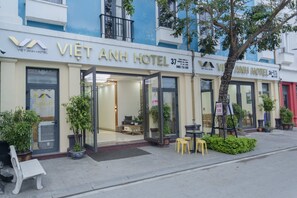 L’extérieur de l’hôtel Việt Anh se distingue par son entrée en verre, son espace extérieur aménagé avec des sièges et ses plantes en pot.