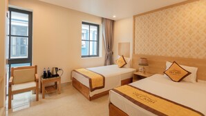 A hotel room with two beds, a chair, a small table with a kettle, and a nightstand with a lamp. - Viet Anh Ha Long Hotel (Bai Chay)