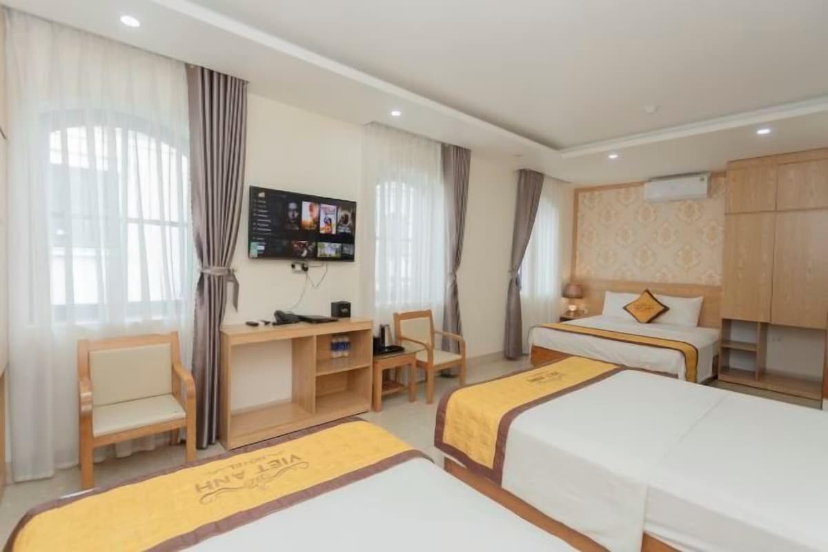 Ett hotellrum med två sängar, ett skrivbord, en TV och en garderob.