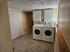 A laundry room with two front-loading washing machines, a window, and a door.