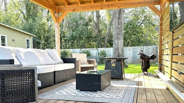 An outdoor deck with wooden flooring, a ceiling fan, and a seating area with a sofa and a table.