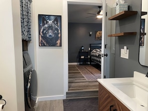 A modern bathroom with a white sink, wooden cabinets, and a shower area.