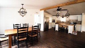 Une cuisine spacieuse avec des poutres apparentes, un coin repas avec une table et des chaises en bois, et un îlot central doté de tabourets.