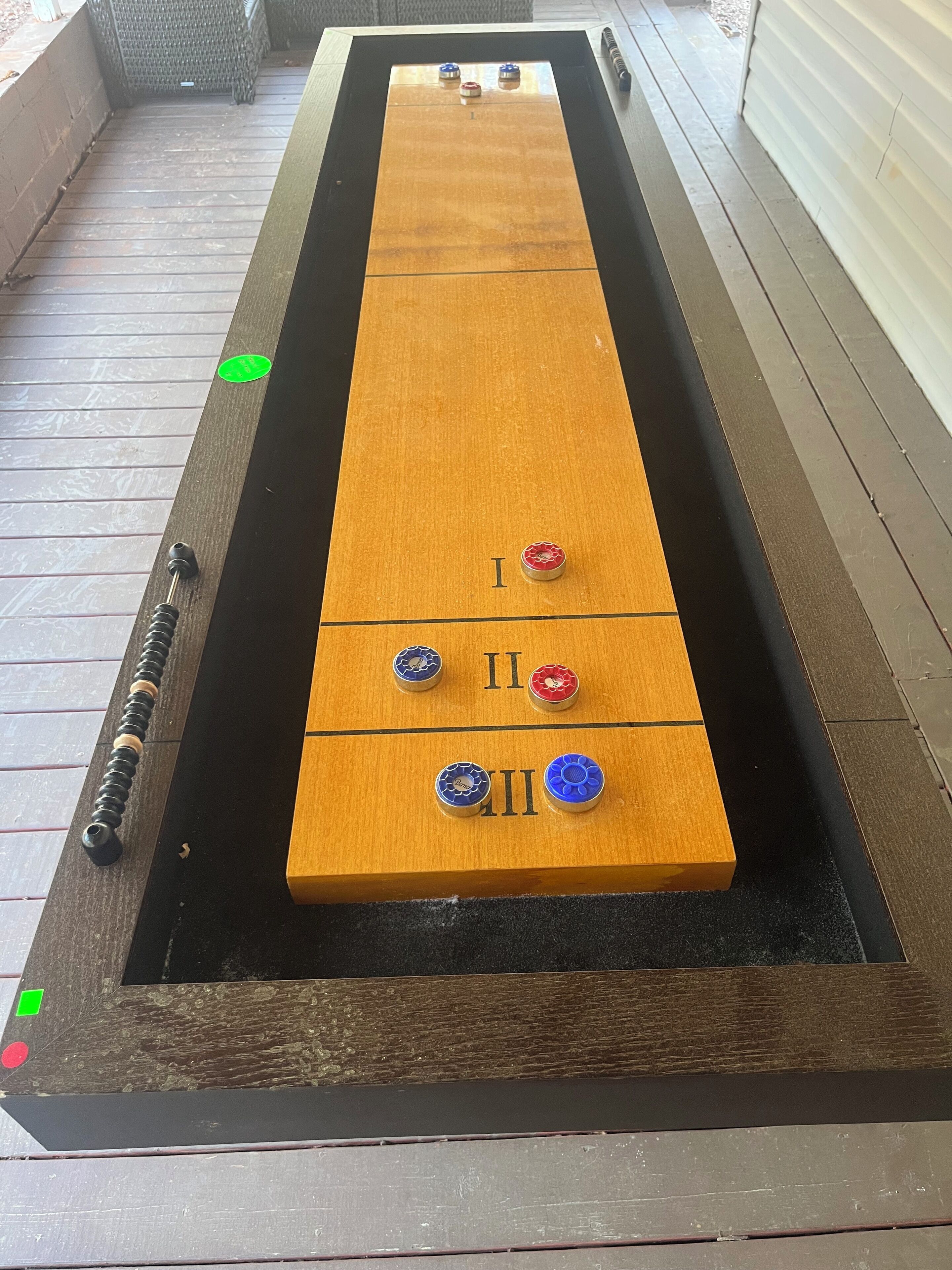 A shuffleboard table with three scoring areas marked I, II, and III.
