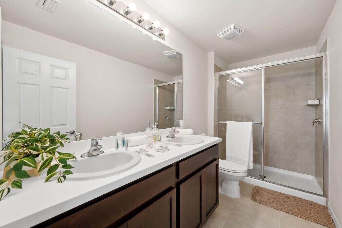 Une salle de bain moderne avec un meuble-lavabo à deux vasques, un grand miroir et une douche à parois de verre.