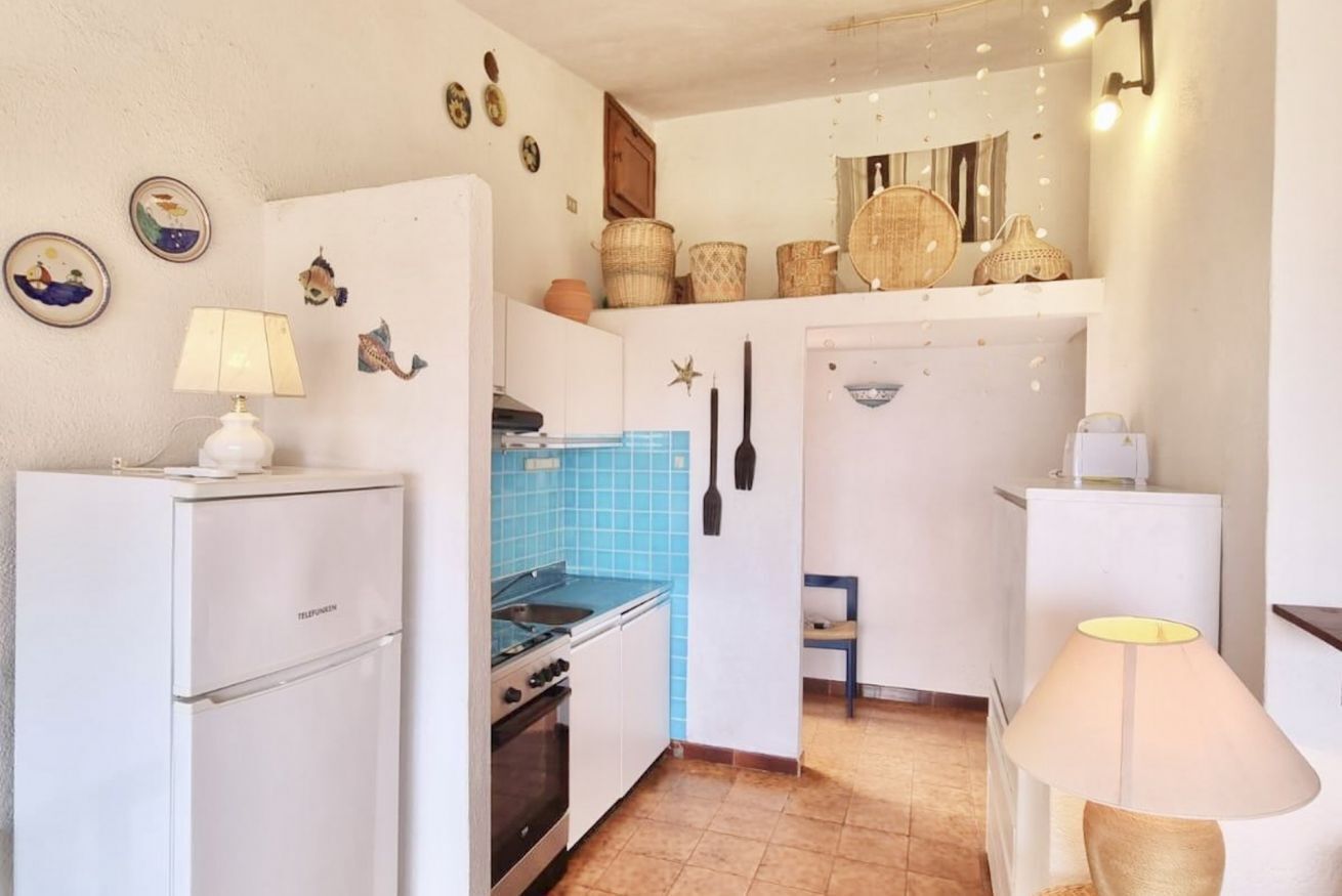 Cocina compacta con refrigerador, estufa y salpicadero azulado de azulejos.