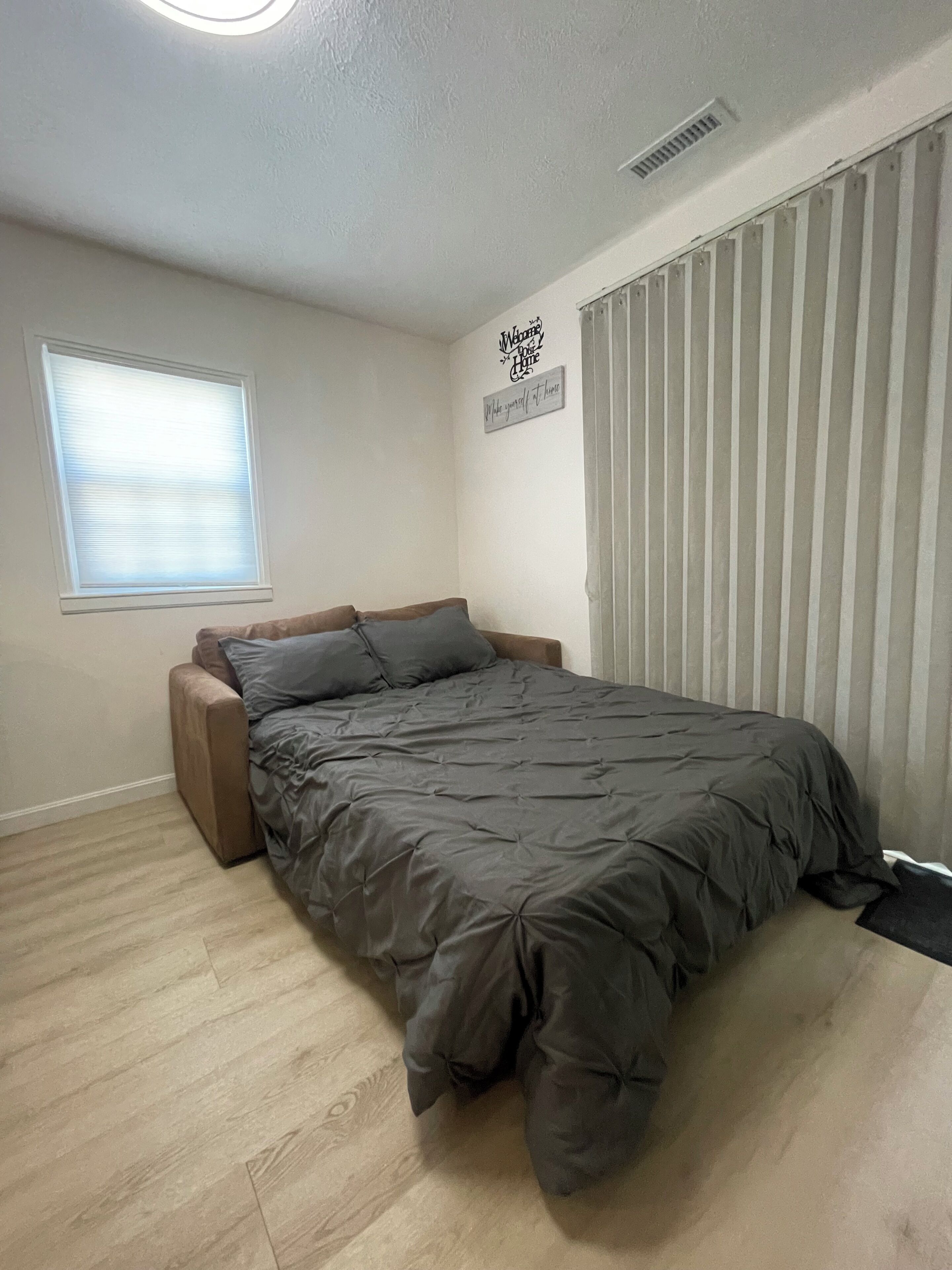 Un dormitorio con cama, ventana, cartel en la pared y radiador.