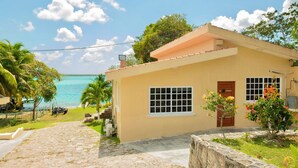Une maison de plain-pied avec un chemin de pierre menant à l’entrée, un petit jardin agrémenté de plantes à fleurs et une vue sur l’océan.