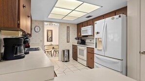 Una cocina compacta equipada con cafetera, microondas, estufa y refrigerador.
