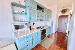 Une cuisine avec des meubles de couleur turquoise, un four à micro-ondes, une cuisinière à gaz et un lave-vaisselle.