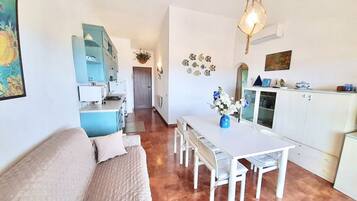 A compact living space with a dining area, kitchenette, and a sofa.