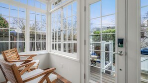A sunroom with large windows, a wooden chair, and a door with a keypad lock. - Game Room, Fire Pit, Sleeps 12, Walkable Retreat (Seattle)