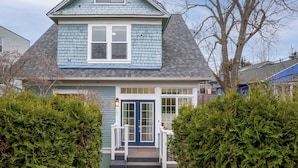 A two-story house with a blue exterior, a front door with glass panels, and a small porch with steps leading up to the entrance. - Game Room, Fire Pit, Sleeps 12, Walkable Retreat (Seattle)