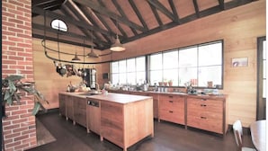 A spacious kitchen with wooden cabinets, a large island, and hanging pots.