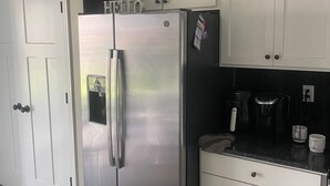 A kitchen with a stainless steel refrigerator, white cabinets, a coffee maker, and a microwave.
