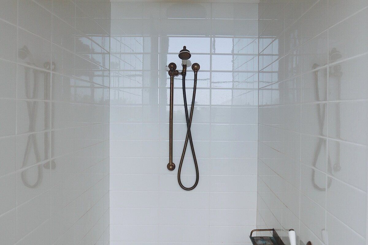 A shower with a handheld showerhead and a wall-mounted faucet.