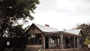 Une cabane rustique dotée d’un porche couvert, d’une cheminée et de fondations en pierre.