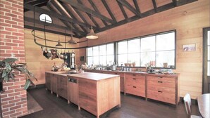 Une cuisine spacieuse avec des meubles en bois, un grand îlot central et des ustensiles de cuisine suspendus.