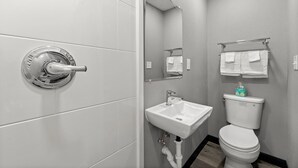 Et moderne badeværelse med toilet, vask og brusebad.