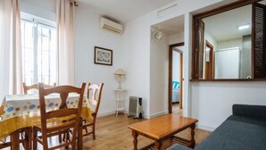 A dining area with a table and chairs, a small lamp, and a radiator. There is a mirror on the wall and a door leading to another room. - Bellas Artes I in Sevilla (Seville)