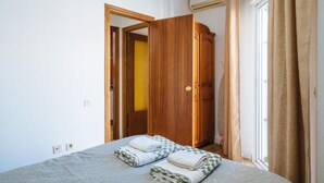 A bedroom with a bed, a wooden wardrobe, and a window with curtains. - Bellas Artes I in Sevilla (Seville)