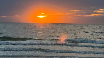 Un coucher de soleil sur l’océan, avec des vagues.