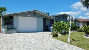 A residential building with a garage, a paved driveway, and a well-maintained lawn. - Private 2BR/2BA Home: Saltwater Pool, Fenced Yard, Sleeps 6 -Custom winter rates (Port Richey)